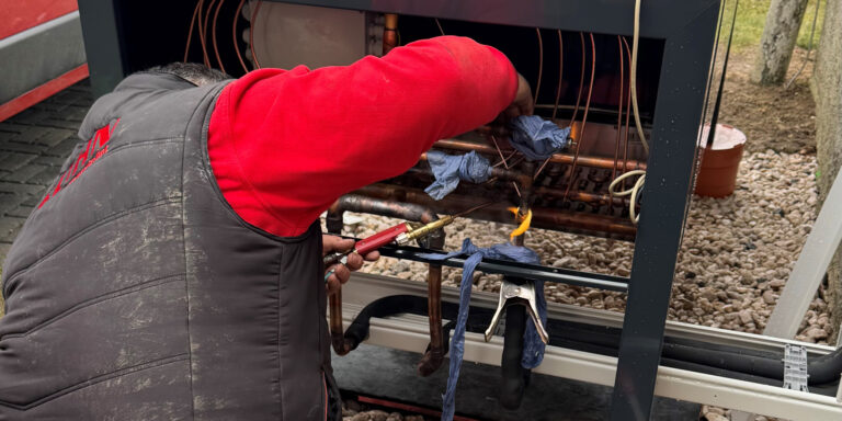 Person lötet Kupferrohre an einem offenen Gerät im Außenbereich